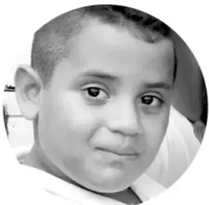 Fotografía en blanco y negro en recorte circular de un niño de primaria mirando de reojo hacia la cámara.