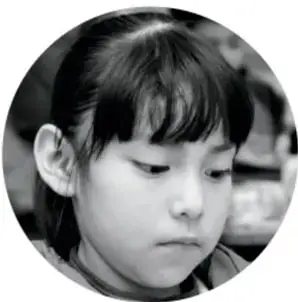 Fotografía en blanco y negro de una niña con el cabello recogido, mirando hacia abajo con expresión pensativa.