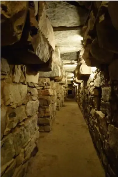 Galería subterránea de piedra con iluminación tenue, probablemente parte de Chavín de Huántar.