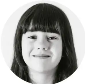 Fotografía en blanco y negro, con recorte circular, del rostro sonriente de una niña de cabello oscuro con flequillo.