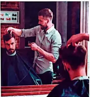 Un peluquero observa el cabello de un cliente mediante un espejo grande.