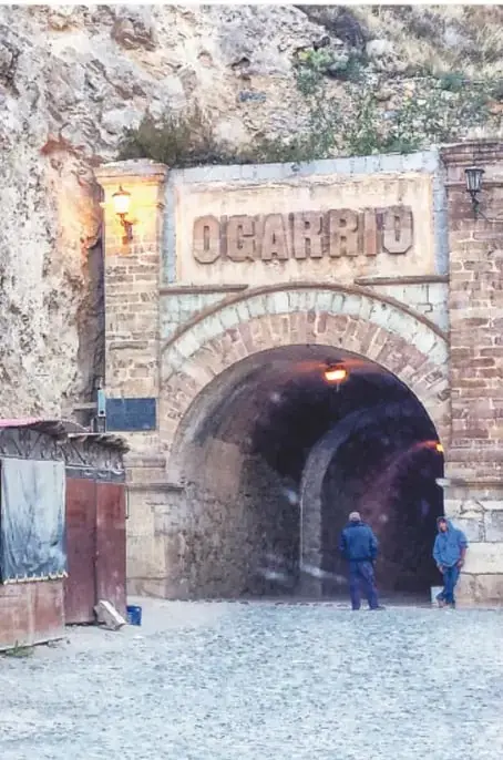 Fotografía de un kiosco blanco de estructura metálica con escalinatas y bancas, rodeado de árboles y montañas, en la plaza de Real de Catorce.