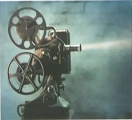 Fotografía de un proyector de cine antiguo con carretes de película, proyectando un haz de luz en ambiente oscuro. Imagen representativa del tema de la proyección cinematográfica. Crédito: Shutterstock (2020) 92369284.