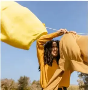 Persona tendiendo ropa amarilla al aire libre en el exterior.