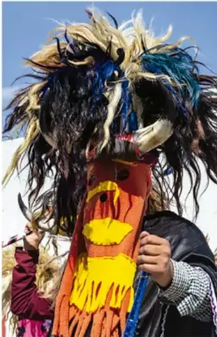 Fotografía de un danzante con penacho de plumas multicolores, máscara y huarache, en una manifestación cultural tradicional. Crédito: Sandra Angélica Martínez Cruz, Baja California.