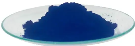 Fotografía de un plato de vidrio con polvo azul intenso de añil, pigmento casi negro.