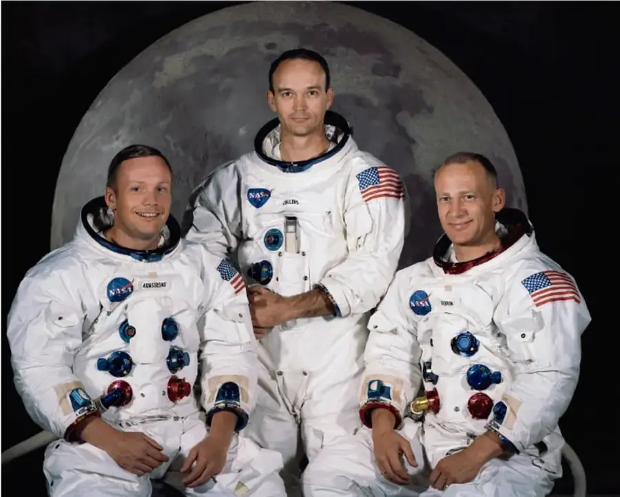 Retrato de los tres astronautas de la misión Apolo 11 con trajes espaciales, frente a una imagen de la Luna.