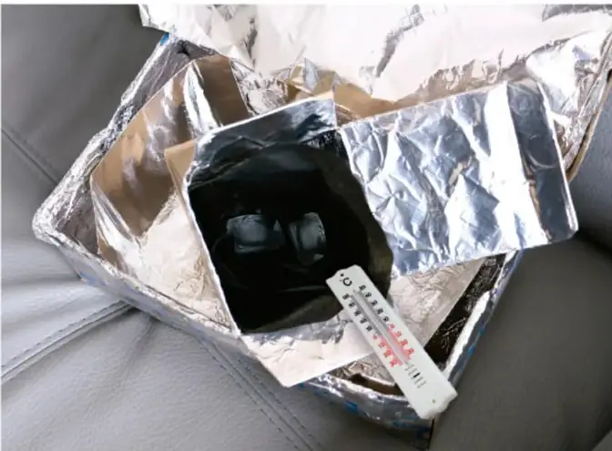 Montaje armado: caja pequeña forrada con papel aluminio y bolsa negra con cubos de hielo en su interior, colocada dentro de una caja grande forrada, con un termómetro apoyado para medir la temperatura.