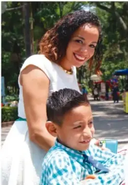 Fotografía de una mujer adulta y un niño sonrientes al aire libre en un parque, abrazándose afectuosamente.