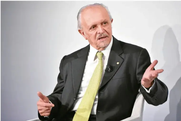 Fotografía del doctor Mario Molina con traje oscuro y corbata amarilla, gesticulando durante una conferencia.