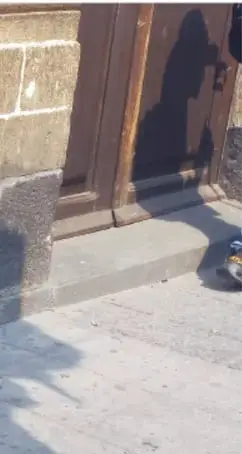 Fotografía de detalle de la esquina del edificio, donde se aprecia la cabeza de serpiente empotrada a nivel de la calle junto a la banqueta.