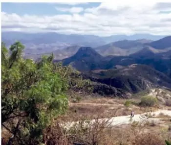 Paisaje de montañas y colinas con vegetación xerófila bajo cielo nublado, representando el medio ambiente.