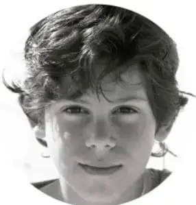 Fotografía circular de un niño sonriente, con cabello oscuro y rizado.
