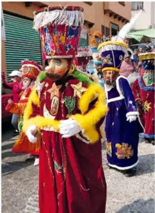 Grupo de chinelos con trajes coloridos y sombreros altos desfilando por las calles durante el carnaval.