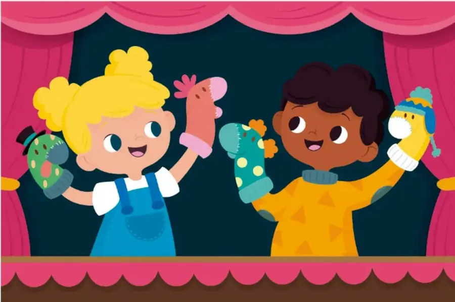 Ilustración de dos niños sobre un escenario con cortinas rosas: una niña rubia con overol azul y un niño de piel morena con suéter amarillo sostienen títeres de calcetín (monstruo verde, cerdito rosa, dragón azul y pollito amarillo).
