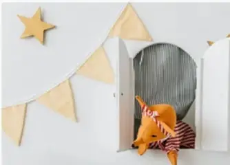 Fotografía de un pequeño teatro de títeres infantil con banderines, estrella y un títeres de animal.