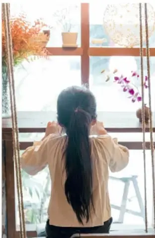Fotografía de una niña sonriente sosteniendo una máscara teatral decorada con flores.