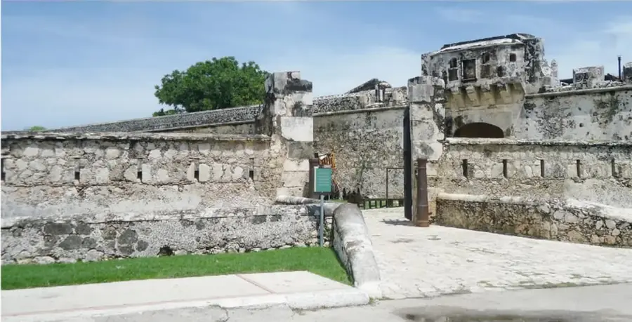 Fotografía panorámica de la muralla de piedra de Campeche, con sus muros, troneras y un baluarte con pasarela de acceso.