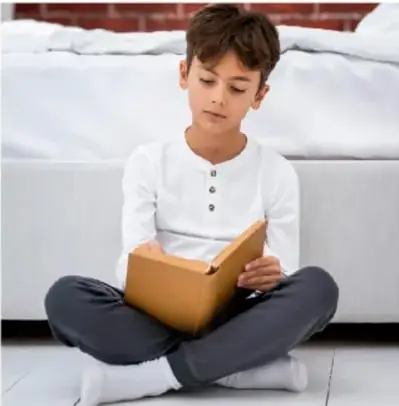 Niño sentado leyendo un libro, con expresión concentrada, como parte del ensayo individual de sus diálogos.