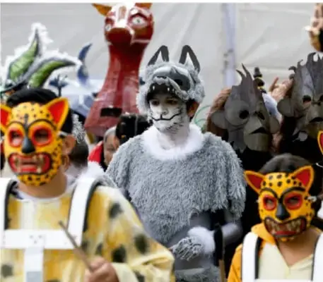 Fotografía de un grupo de personas con máscaras y trajes de felinos y otros animales, aparentemente en una danza o representación tradicional, alusiva a la expresión artística comunitaria.