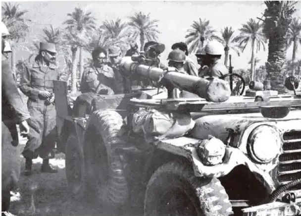 Fotografía en blanco y negro de un vehículo militar con soldados en un entorno desértico con palmeras, probablemente en el norte de África durante la Segunda Guerra Mundial o un conflicto colonial.