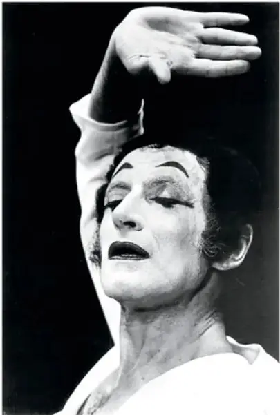 Fotografía en blanco y negro de Marcel Marceau como mimo, con la mano elevada sobre la cabeza y expresión dramática, maquillaje blanco característico.