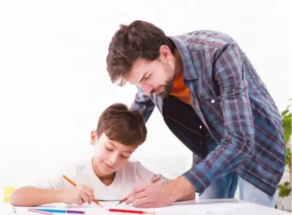 Un maestro ayuda a un alumno a escribir en su cuaderno.