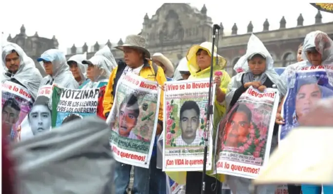 Fotografía de un grupo de personas con pancartas y carteles con rostros de los normalistas desaparecidos, exigiendo su aparición con vida.