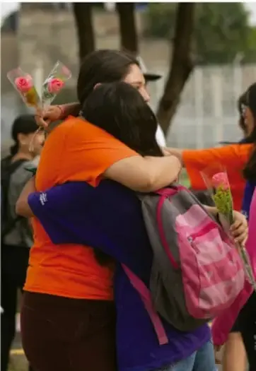 Fotografía de dos personas abrazándose, una con mochila y ramo de flores, probablemente representando un reencuentro familiar o apoyo entre jóvenes.