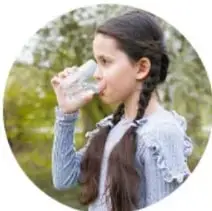 Niña bebiendo agua de un vaso.