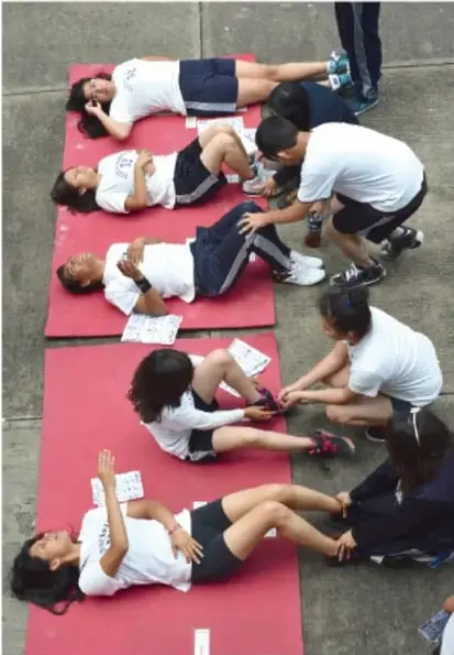 Estudiantes en colchonetas realizando actividades físicas guiadas por instructores.
