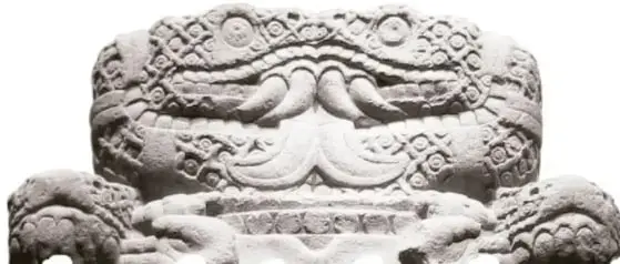 Escultura de piedra de la Coatlicue, con rostro dual, garras y falda de serpientes.