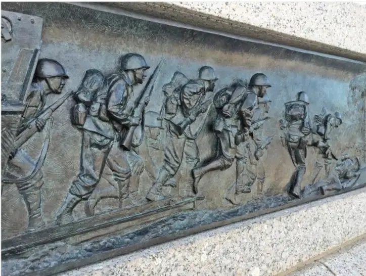 Relieve en bronce que muestra a soldados con cascos, mochilas y rifles marchando en formación, evocando a los combatientes de la Primera Guerra Mundial.