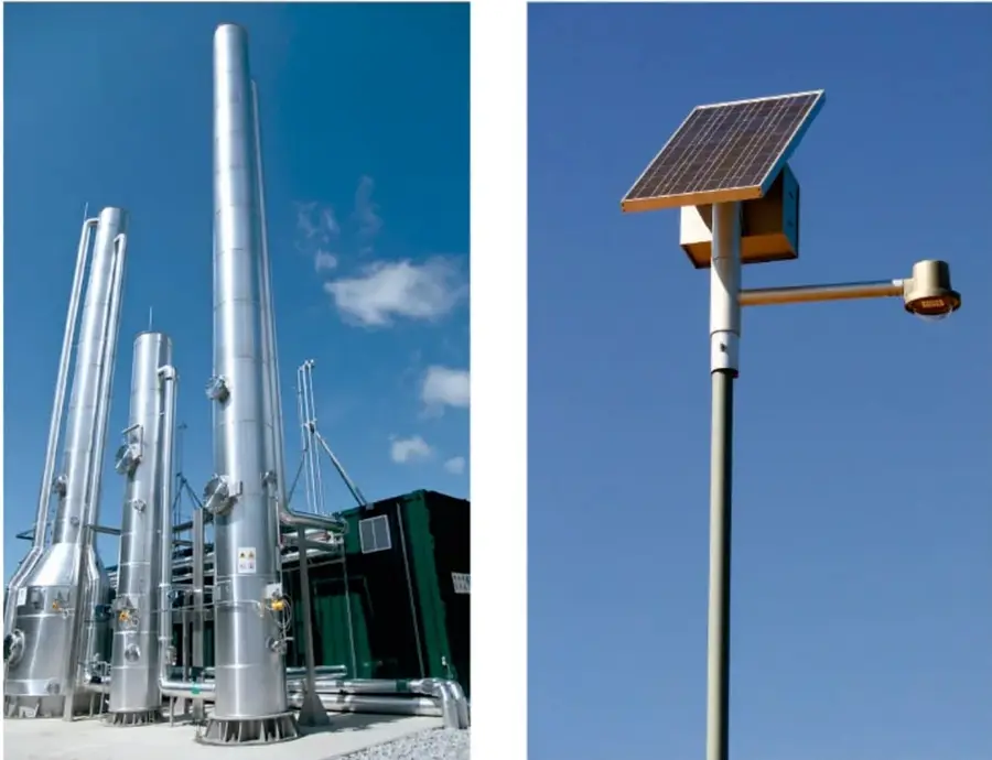 Planta industrial con varias torres y tuberías metálicas reflectantes sobre cielo azul.
