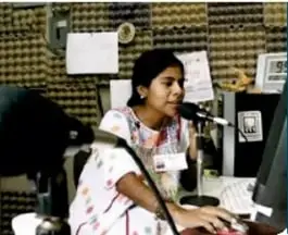 Mujer indígena hablando frente a un micrófono en una radio comunitaria.