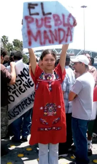 Fotografía de una niña sosteniendo un cartel que dice "EL PUEBLO MANDA" durante una manifestación.