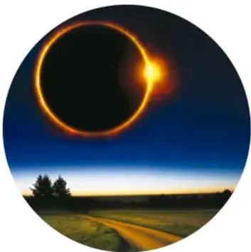 Foto circular de un eclipse de Sol anular/total con el anillo luminoso del Sol alrededor de un disco oscuro sobre un paisaje al atardecer.