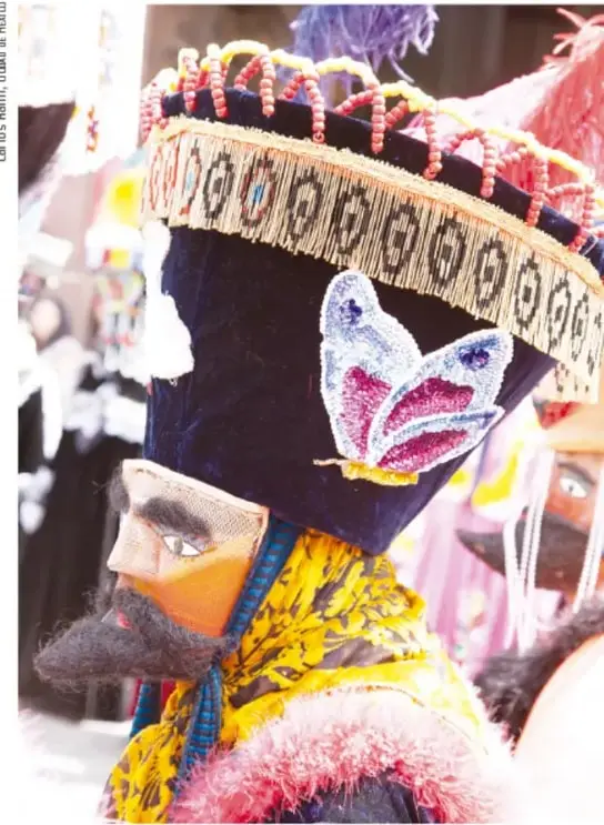 Máscara ovalada cubierta de chaquira: figuras geométricas de estrellas y flores en rojo, verde, amarillo, azul y blanco, con aberturas para ojos y boca.