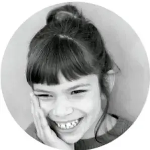 Fotografía de una niña sonriente con las manos en el rostro.