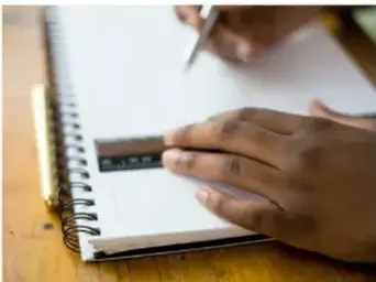 Manos midiendo con un instrumento sobre un cuaderno (medición directa).
