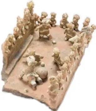 Pieza de barro pequeña que representa una escena de juego de pelota con figuras humanas modeladas, probablemente una maqueta o figurilla de cancha.