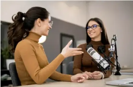 Fotografía de dos mujeres conversando frente a un micrófono, ilustrando una entrevista (fuente de información personal).