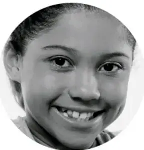 Fotografía de una niña sonriente, con cabello recogido, mirando a la cámara.