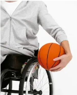 Persona en silla de ruedas sosteniendo un balón de básquetbol, representando inclusión y diversidad.