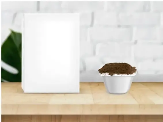Caja de zapatos cerrada junto a un recipiente blanco con tierra sobre una superficie plana de madera.