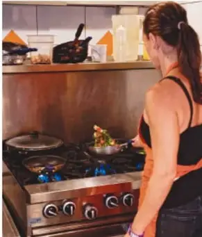 Fotografía de una mujer cocinando en una estufa con varias sartenes, ilustrando roles domésticos.
