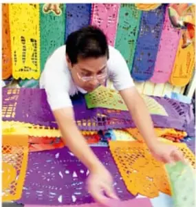 Artesano recortando con herramienta un papel rosa sobre base; foto de Rosa Laura Tezoco Tehuintle, Veracruz.