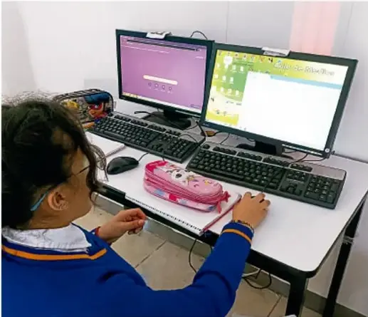 Fotografía de una estudiante trabajando en una computadora de escritorio con dos monitores, crédito Luis Eduardo García Medel, TLAXCALA.