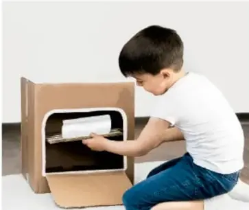Niño colocando un recipiente dentro de un mueble oscuro.