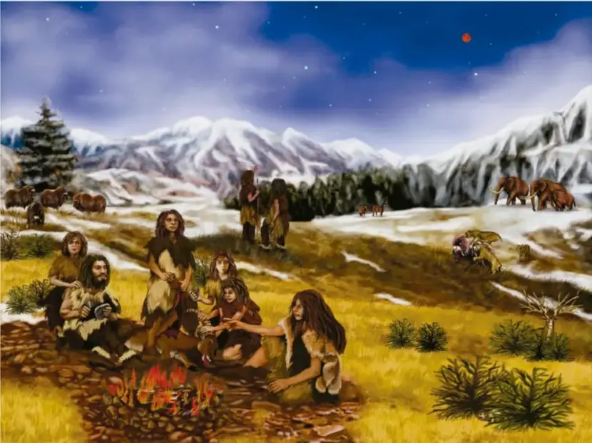 Ilustración de un grupo de seres humanos primitivos junto a una fogata en un paisaje con montañas nevadas, animales salvajes (mamuts, caballos) y vegetación, representando los inicios de la ocupación humana de la Tierra.